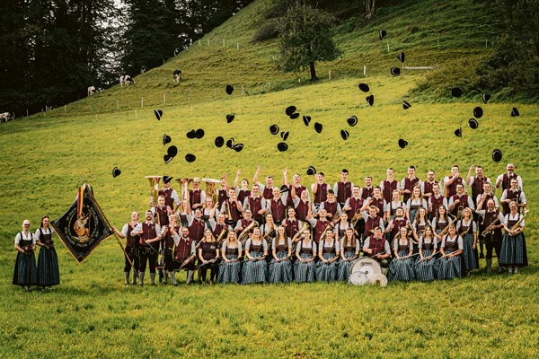 Die Mitglieder der Musikkapelle Maierhöfen mit deren Instrumente und Flagge. Es werden Hüte in die Luft geworfen.