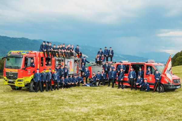 Feuerwehr Sigmarszell Zu sehen sind die aktiven Mitglieder der Freiwilligen Feuerwehr Sigmarszell. Dabei 2 Feuerwehrautos und Fahne.