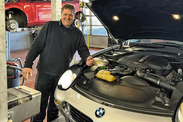 Thomas-Fuchs Thomas Fuchs, KFz-Meister vor einer geöffneten Motorhaube eines BMW-Fahrzeuges.